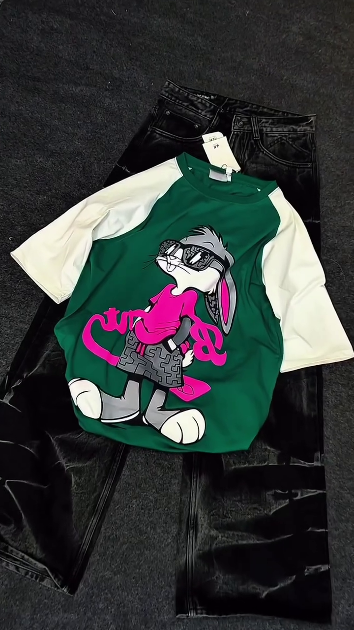 Green & White Raglan Cartoon Shirt 💚🤍👕 with Playful Graphic 🎨 Paired with Black Shiny Pants 🖤👖 Casual Pop-Culture Ensemble ✨