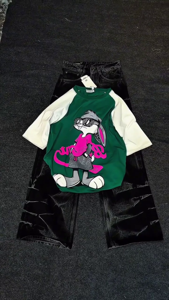 Green & White Raglan Cartoon Shirt 💚🤍👕 with Playful Graphic 🎨 Paired with Black Shiny Pants 🖤👖 Casual Pop-Culture Ensemble ✨