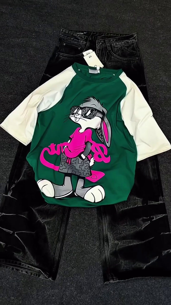 Green & White Raglan Cartoon Shirt 💚🤍👕 with Playful Graphic 🎨 Paired with Black Shiny Pants 🖤👖 Casual Pop-Culture Ensemble ✨